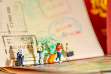 Miniature toys concept studio set up - expatriate business man arrives or departs with visa passport stamps as the background. Side lighting with vintage yellowish filter for evening sunset light.
