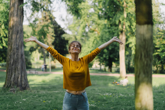 Young woman in a park with outstretched arms