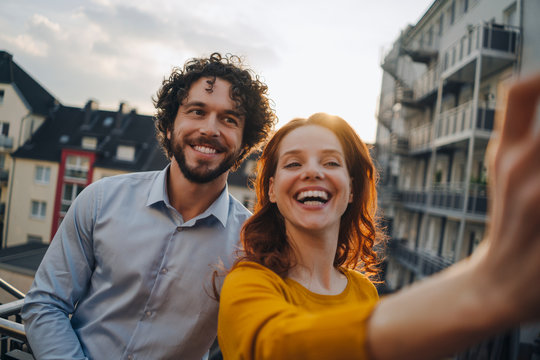 Two happy colleagues on roof terrace taking a selfie