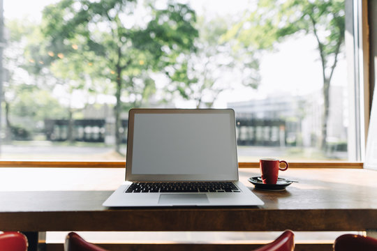 Laptop and cup of coffee on table in a cafe