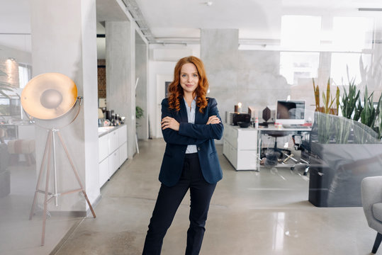 Portrait of confident redheaded businesswoman standing in office