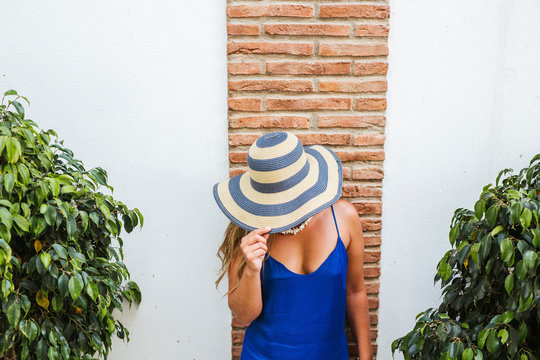 Woman wearing blue dress and straw hat standing in front of wall, Nerja, Spain