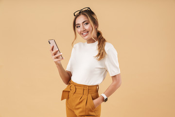 Image of attractive young woman smiling and holding smartphone