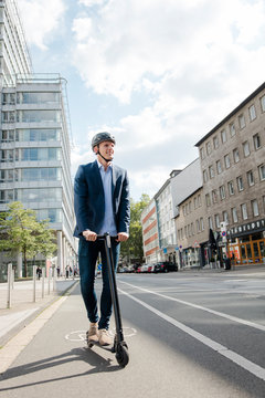 Young businessman riding e-scooter on bicycle lane in the city