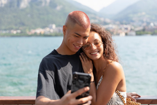 Portrait of happy young couple taking selfie in front of Lake Como, Lecco, Italy