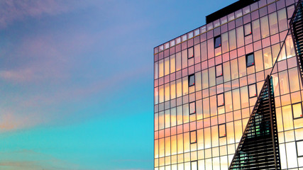 Fototapeta premium Beautiful colorful sunset reflecting on windows skyscraper facade building architecture