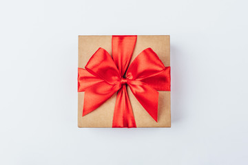 Cardboard gift box with red bow on white background.