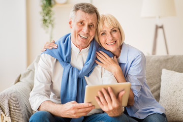 Excited mature couple with digital tablet smiling to camera