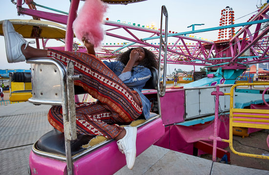 Laughing young woman with pink candy floss at fair