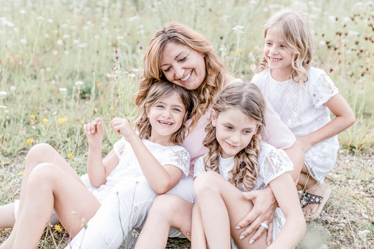Happy mother with three triplet daughters in a field