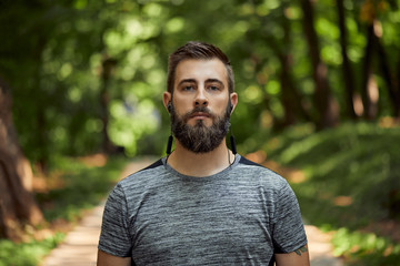 Portrait of sporty man with earphones in forest