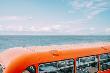 Orange vintage bus over sea