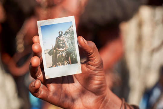 Mudimba tribe woman showing a picture of herself, Onocua, Angola.