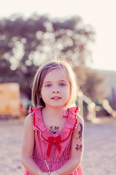 Portrait of little girl with temporary tattoos at sunset