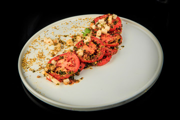 top view on sliced tomato originally decorated with assorted herbs