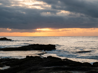 Obraz premium sunrise on rocky beach with orange light