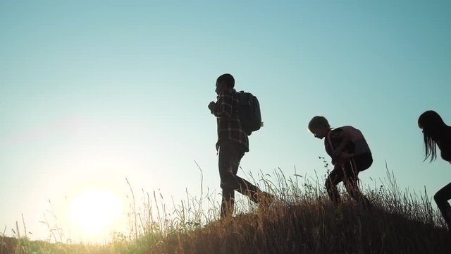 people hikers teamwork a happy family with backpacks group and the dog silhouette of sunlight of tourists four people walking on top of a sunset silhouette mountain. parents and children slow video