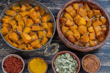 Baked yellow pumpkin with honey, anise, olive oil and spices on a plate on the wooden table. Vegetarian food. Closeup