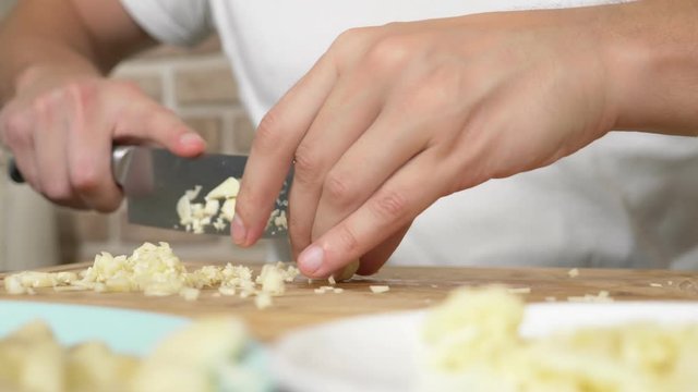 male hands cut garlic on a wooden board. close-up