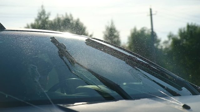 Closeup of windshield and wipers. Windshield washer on. Slow motion.