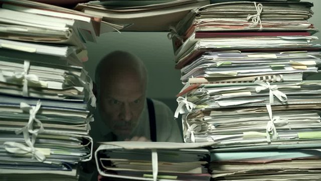 Office clerk working behind a wall of paperwork
