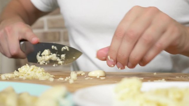 male hands cut garlic on a wooden board. close-up