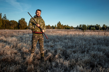 Hunter man in camouflage with a gun during the hunt in search of wild birds or game on the...