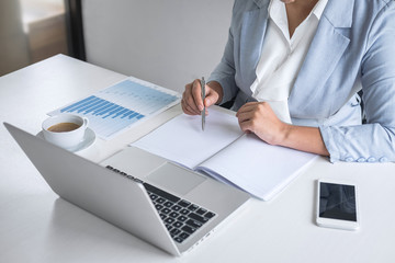 Business woman accountant financier working audit and calculating expense financial annual report balance sheet statement, doing finance checking document and making notes on report paper