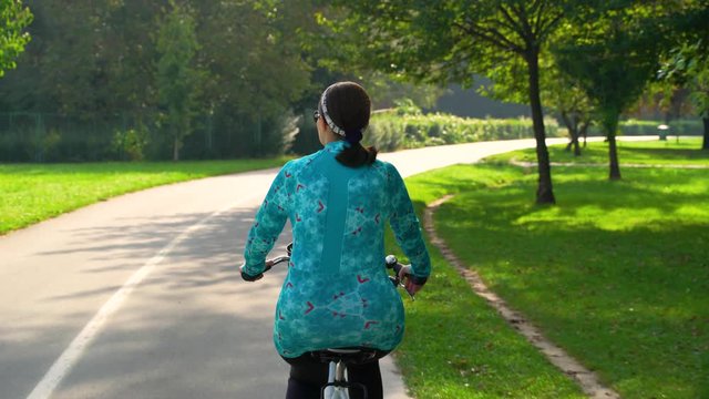Woman riding a bicycle during sunrise at park, Zagreb, Croatia.