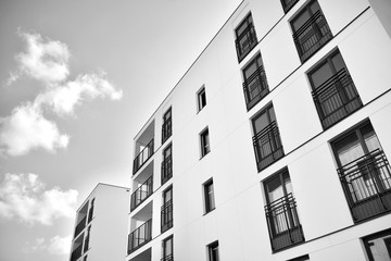  Fragment of a facade of a building with windows and balconies. Modern home with many flats. Black and white.