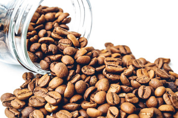 Roasted coffee beans rolling out of a glass jars isolated on white background.