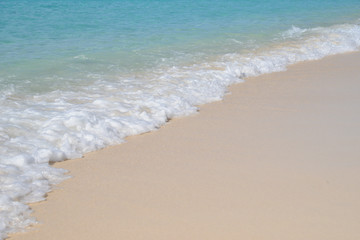 Fototapeta na wymiar Turquoise ocean with gentle waves breaking on a beautiful golden sandy beach