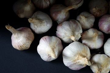 Shot of several whole garlic bulbs grouped on black plate