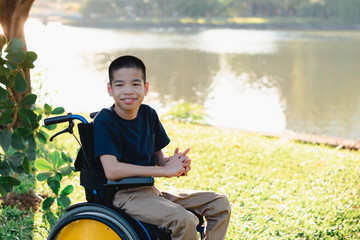 Fototapeta premium Disabled child on wheelchair is playing, learning and exercise in the outdoor city park like other people,Lifestyle of special child,Life in the education age of children,Happy disability kid concept.