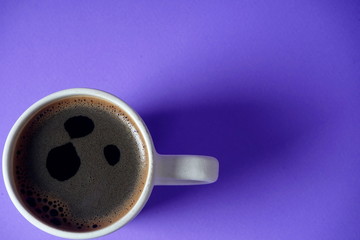 White Cup with black coffee on lilac background. Rest, relaxation, tone.