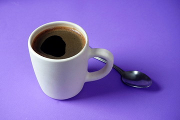 White Cup with black coffee on lilac background. Rest, relaxation, tone.