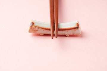 Wooden chopsticks and chopstick rest on bright paper background. Close up. Copy space. 