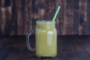 Fresh green smoothie from avocado, kiwi, banana and honey in glass mug on wooden background, closeup. Concept of healthy eating