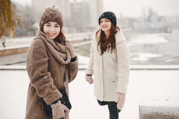 two bright and merry girls walking in the frozen snowy park