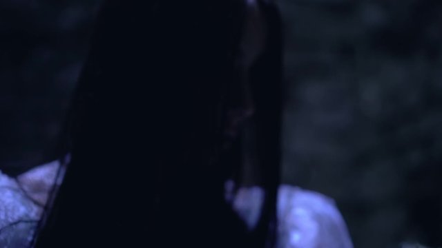 Insane young woman rocking creepy baby doll in dark room, psychotic disorder