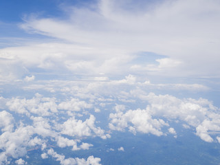 Fototapeta premium Clouds from airplane window with blue sky and high angle ground
