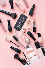 Obraz premium Makeup cosmetic perfume women products accessory pouring from shopping bag on pink flat lay background, beauty products cheap discount retail offer online purchase, top view above vertical photo