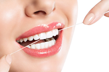 Young beautiful woman is engaged in cleaning teeth. Beautiful smile healthy white teeth. A girl holds a dental floss. The concept of oral hygiene. Promotional image for a dental clinic.