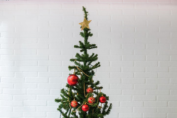 christmas tree with ornaments on white brick wall background