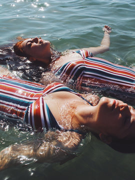 Women in bathing suits floating on their backs