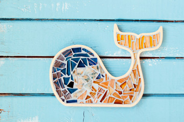 Whale with blue mosaic on blue wooden background.