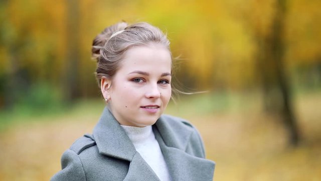 Autumn portrait of a young girl in an autumn park in a gray coat. Posing at a photo shoot in nature.