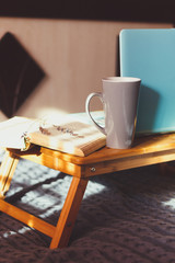 Home workplace. Table with blue laptop in bed.