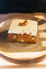 Almond coffee cake in square shape topping with white cream and cashew nut.