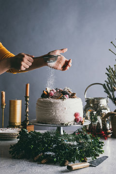 Woman's hand sprinkling powdered sugar on cake
